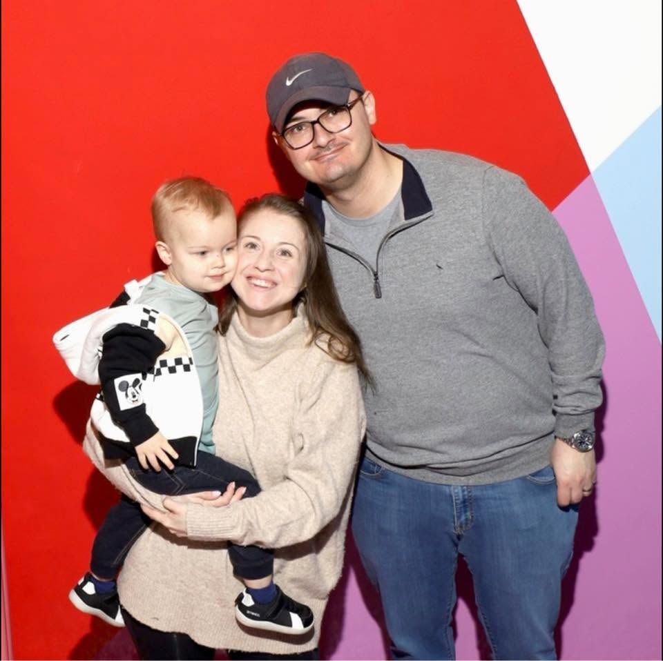 Greene House Studios photographer Megan Greene smiling with her husband Sam and their son Andy in a colorful family portrait.