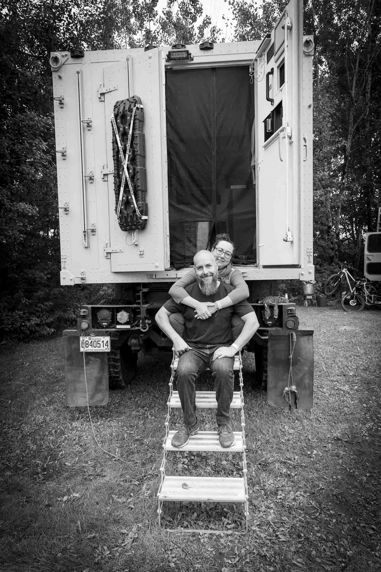 Val et Phil
Black and white photo of two people posing on truck steps, smiling in front of a large military-style vehicle outdoors.