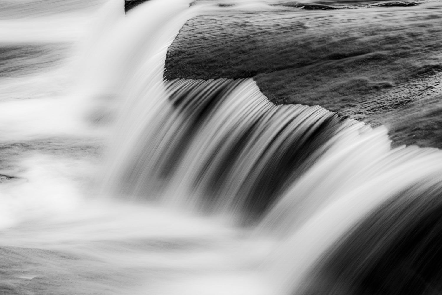 Chute d'eau, pose longue
Québec, Canada
Black and white long exposure photograph of a cascading waterfall flowing over smooth rocks.