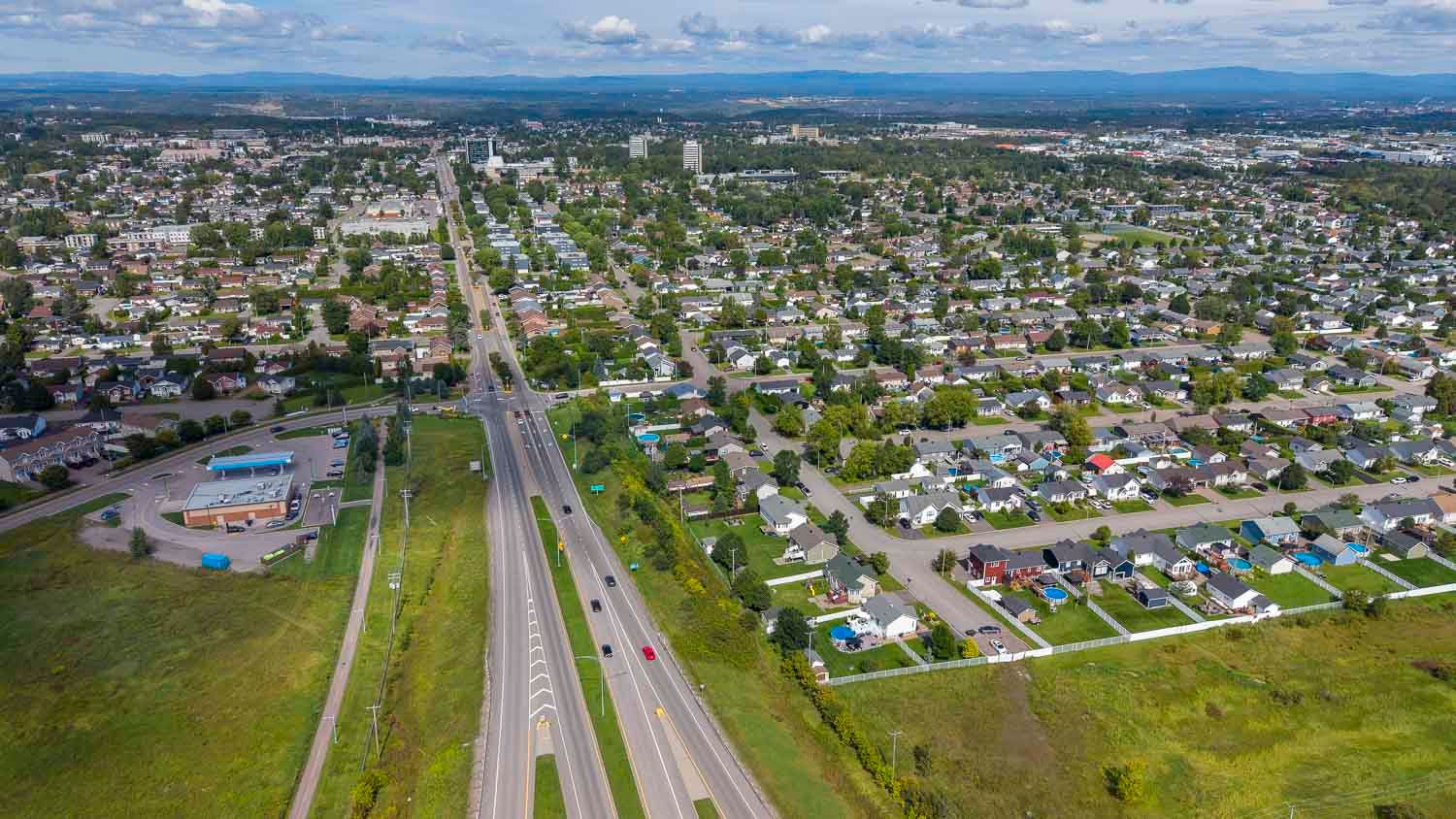 Ville de Jonquière, Qc, Canada
Aerial view of a suburban city with a highway running through green neighborhoods.
