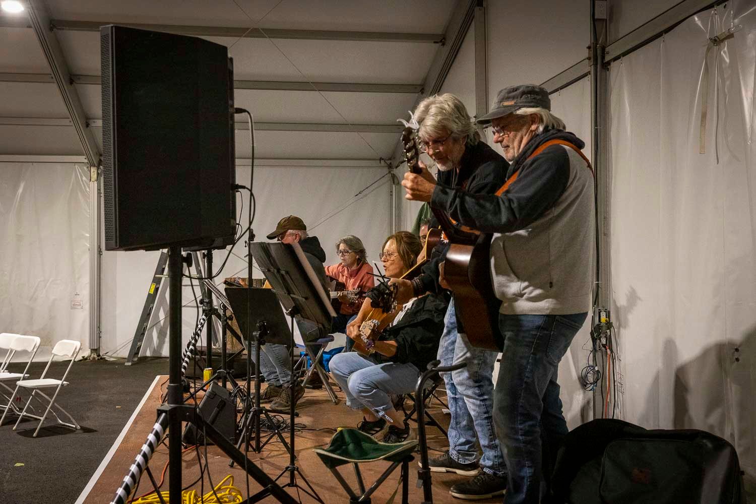Musicians performing live on stage under a tent at an outdoor festival event.