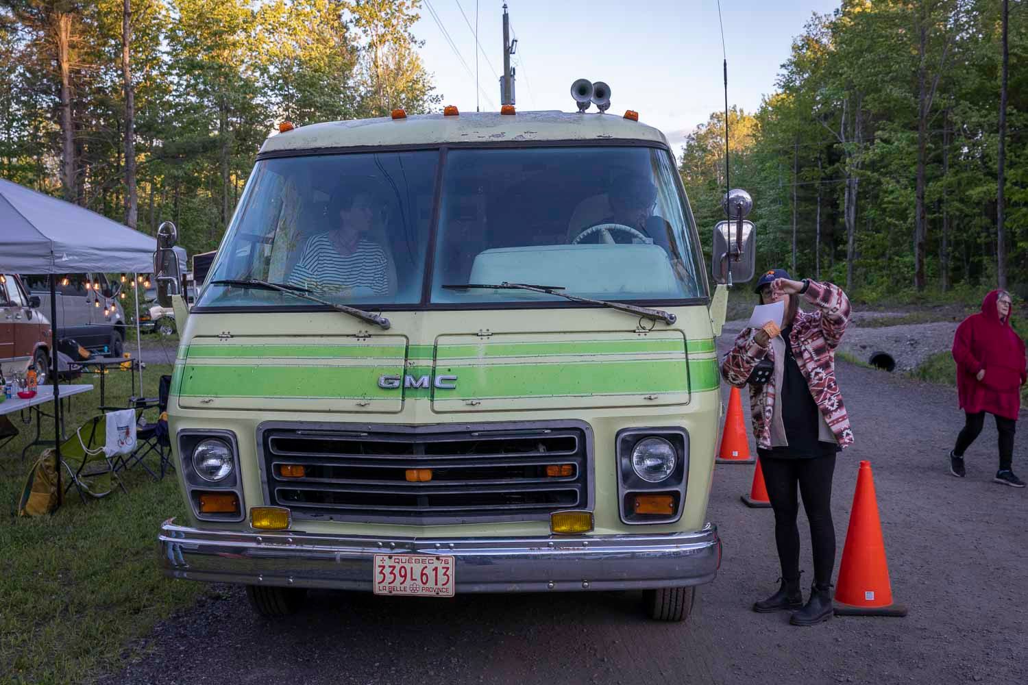 Front view of a classic green Chevrolet van parked outdoors with orange safety cones.