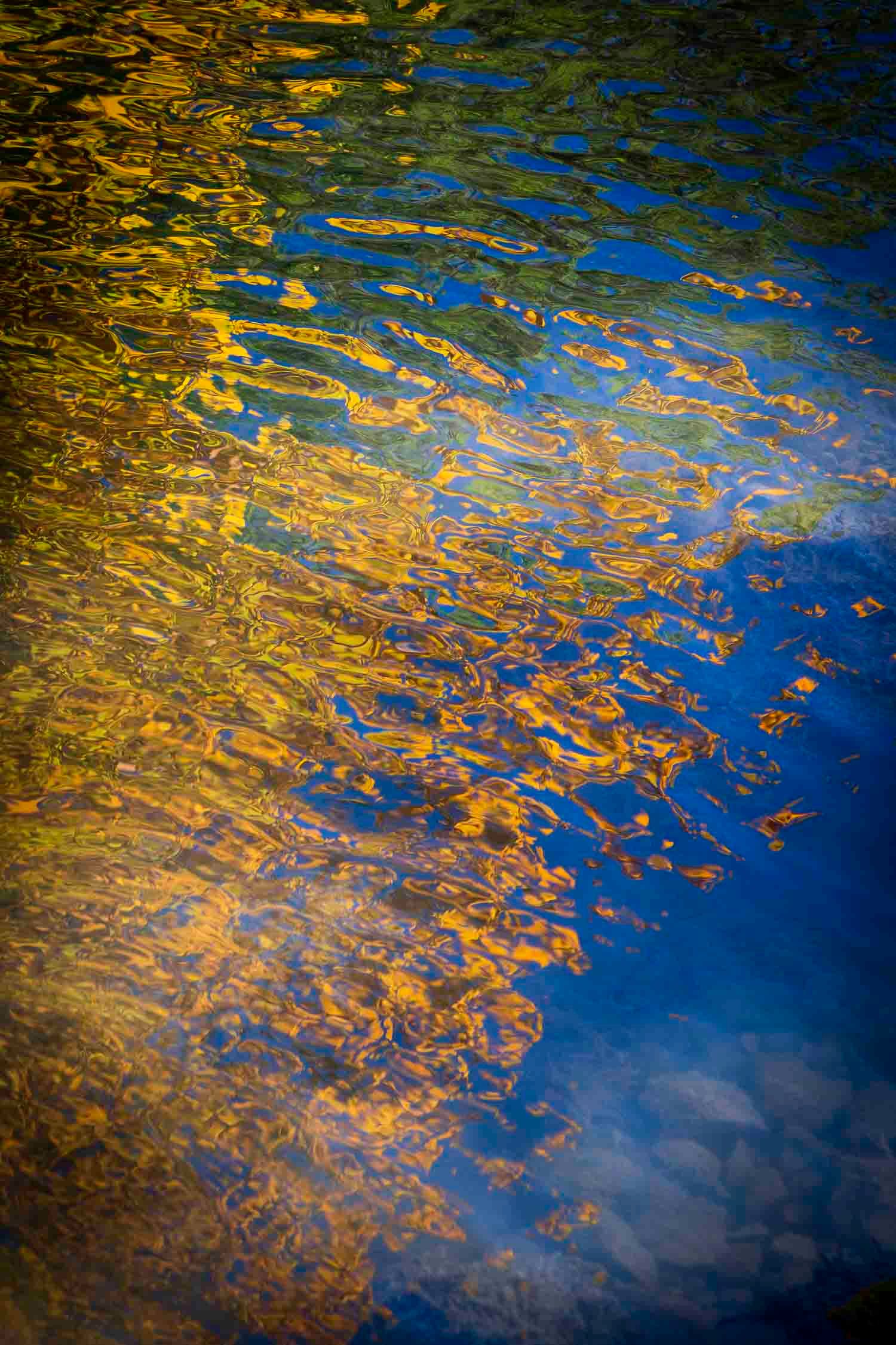 Reflets d'automne sur l'eau
Québec
Abstract water surface reflecting golden autumn leaves and blue sky, creating colorful rippling patterns.