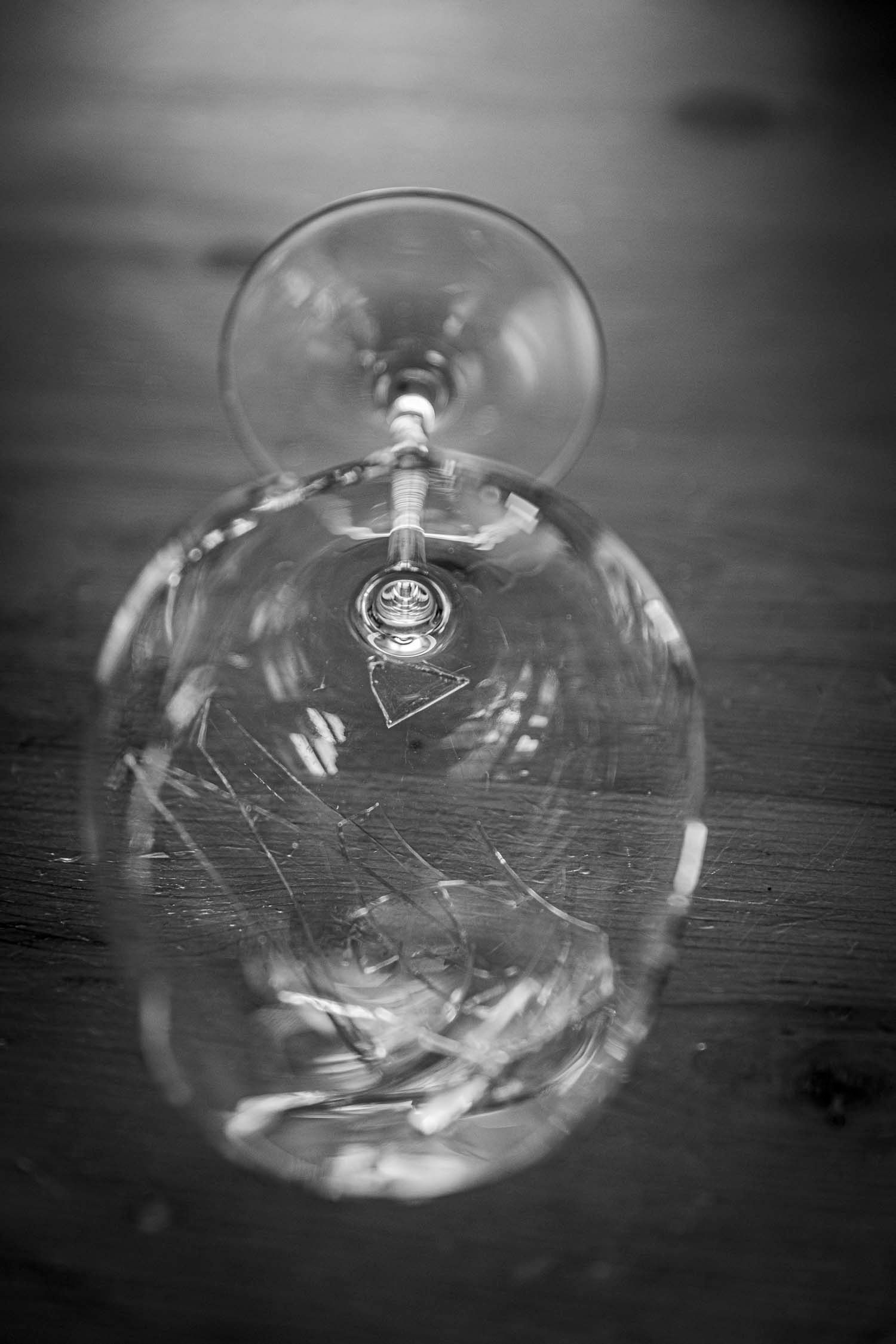 Black and white artistic photo of an upside-down crystal wine glass on a wooden surface.