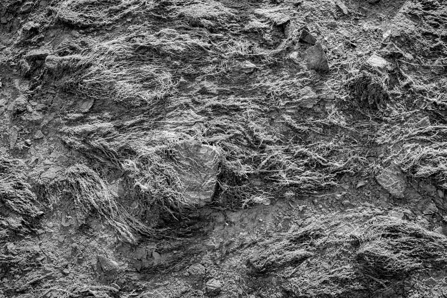 Close-up black and white texture of rough rugged rocky stone surface.