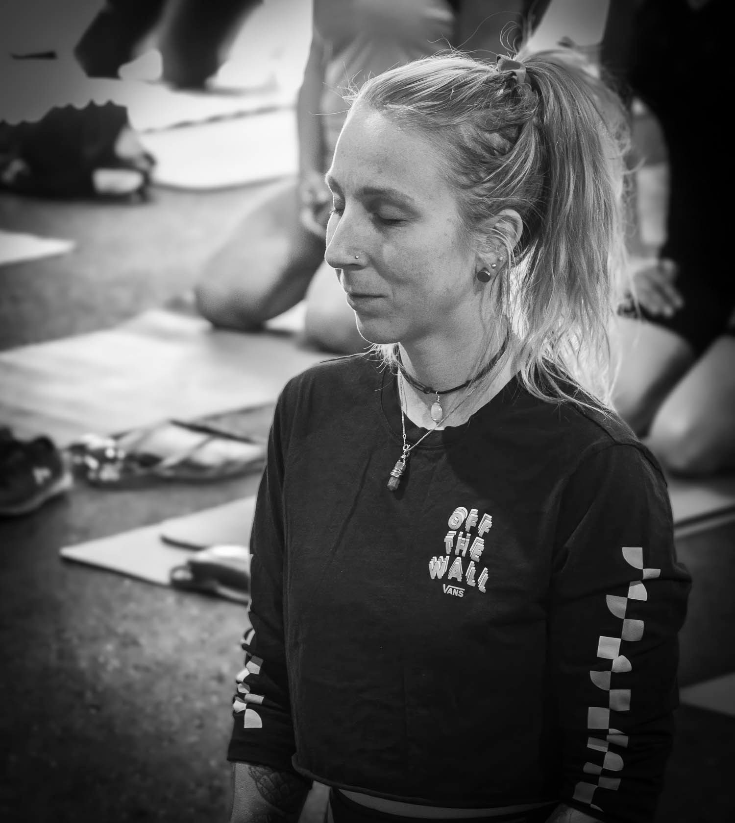 Black and white portrait of a woman with ponytail in a Vans off the wall shirt meditating eyes closed.