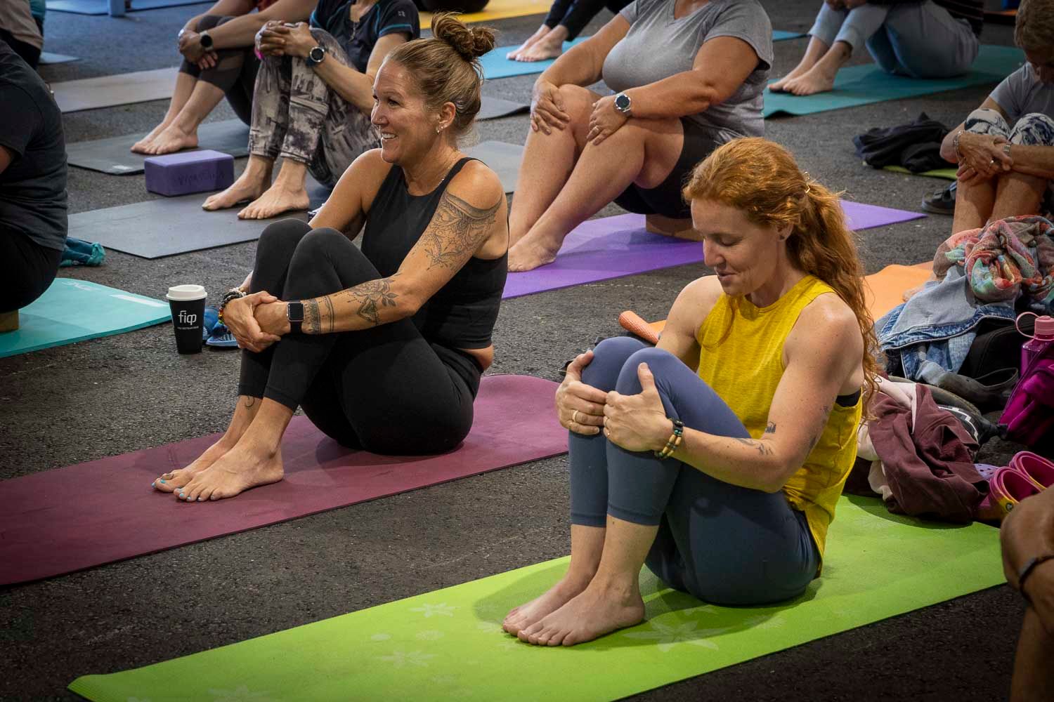 Two women practicing yoga on colorful mats during a group yoga session indoors.