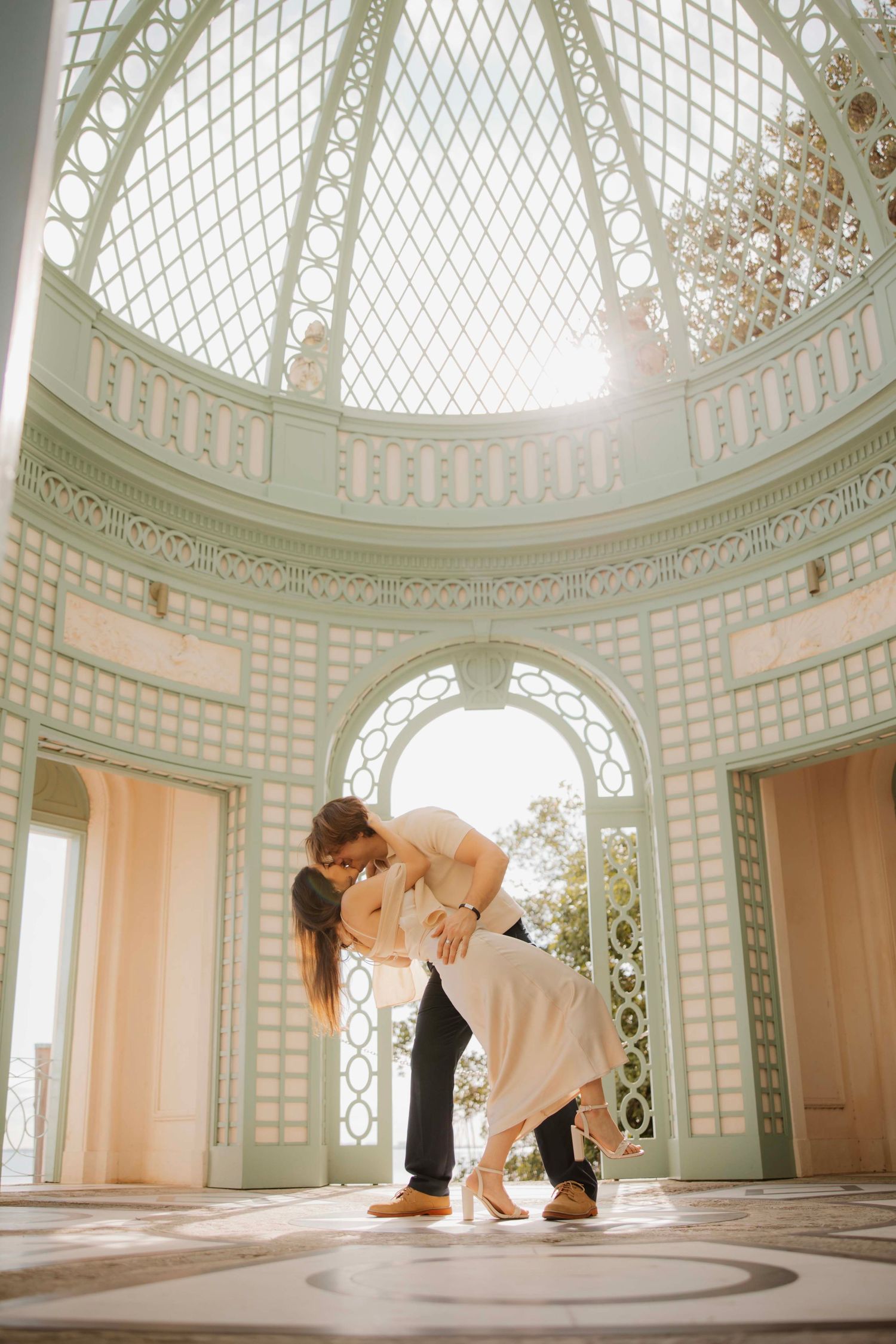 A romantic dance pose in an elegant white gazebo with intricate lattice details.
