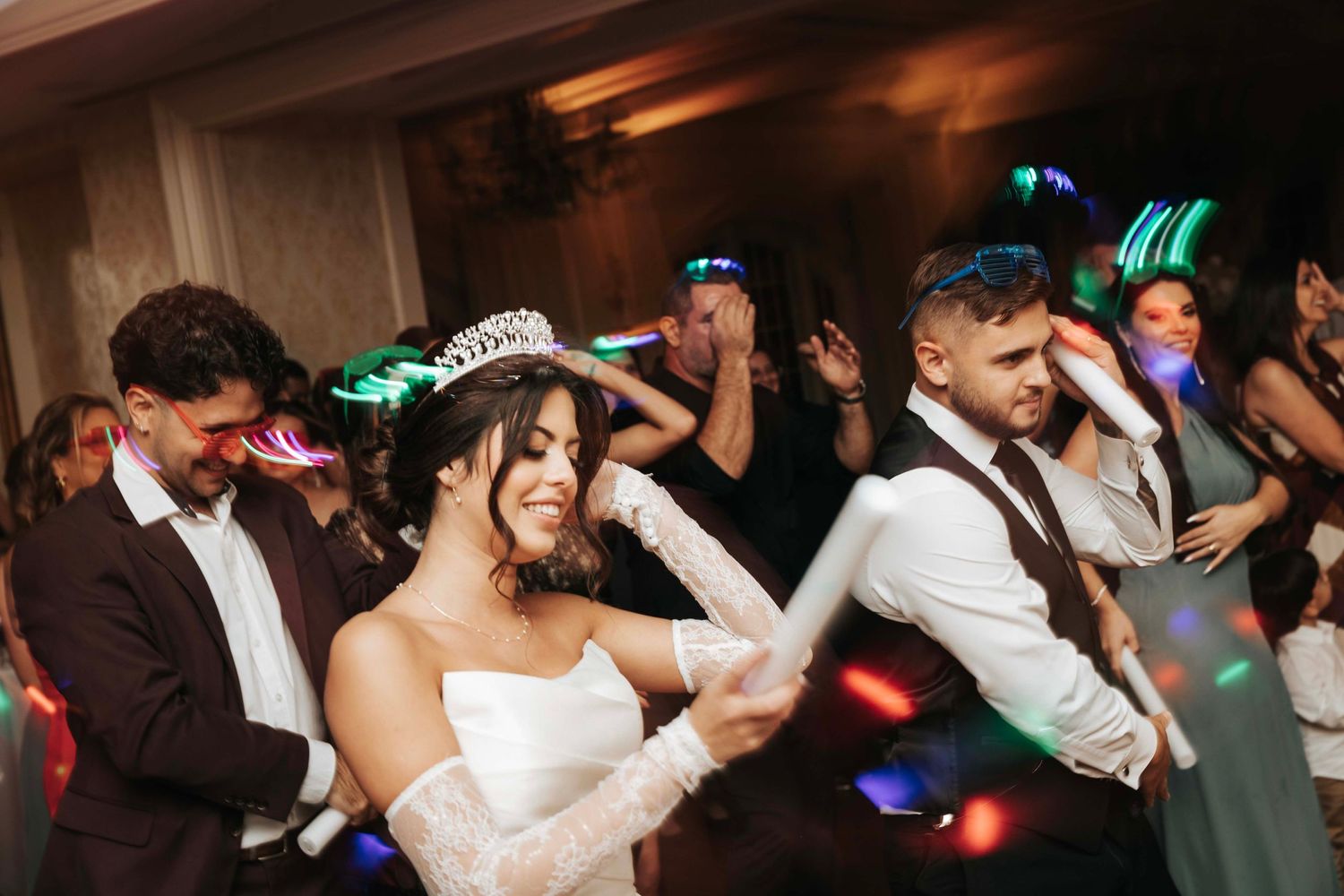 Wedding celebration on the dance floor with colorful party lights and glowing accessories.