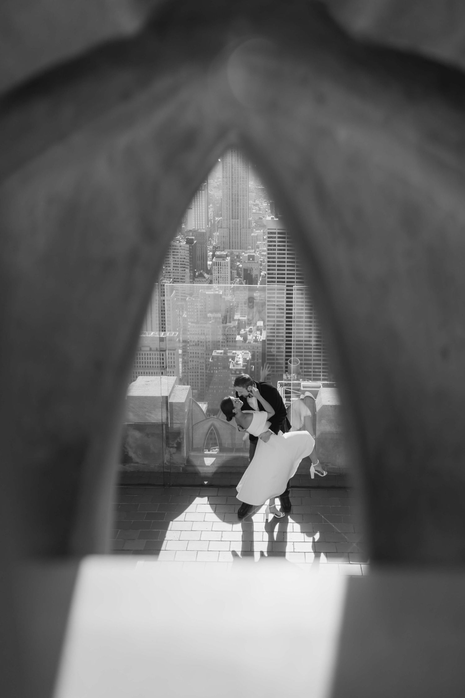 Artistic wedding photo framed through veil showing couple dancing in black and white.