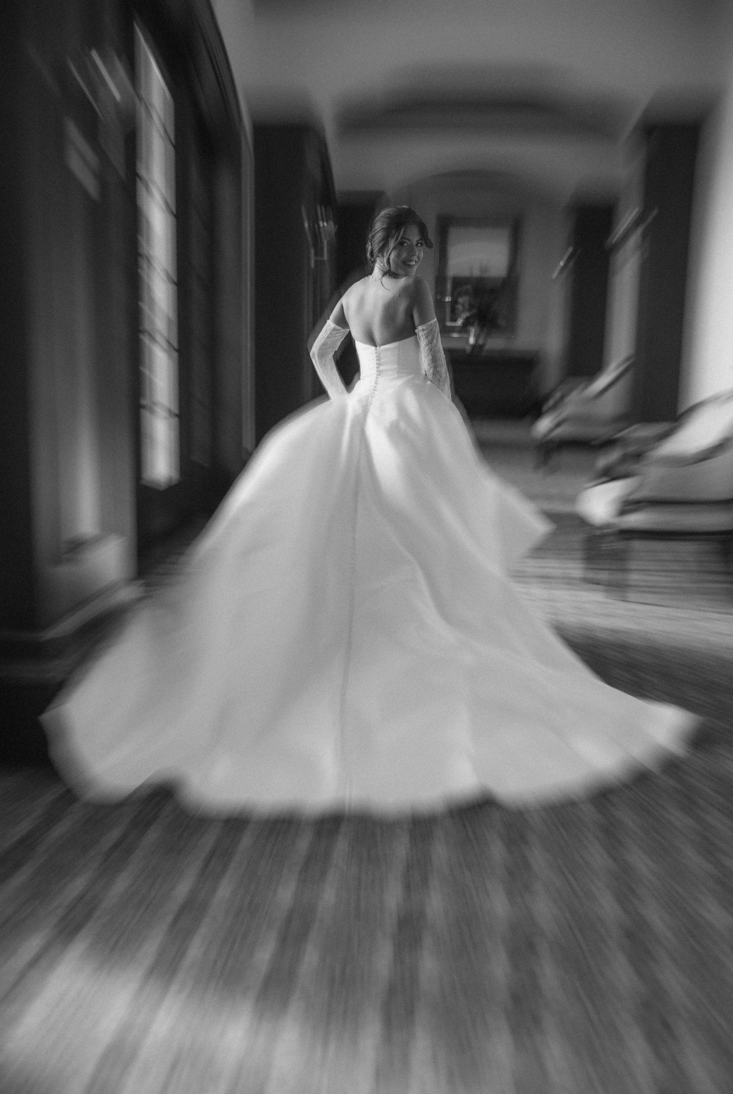 Motion blur photo of bride twirling in a ballgown wedding dress with dramatic train.