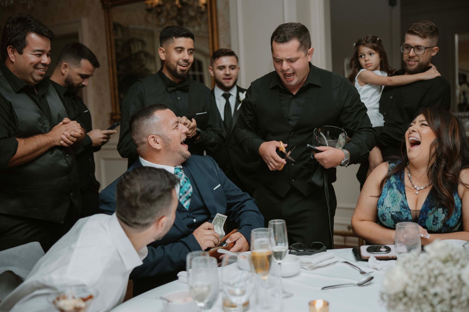 Candid moment of wedding guests laughing and enjoying themselves at a reception table.