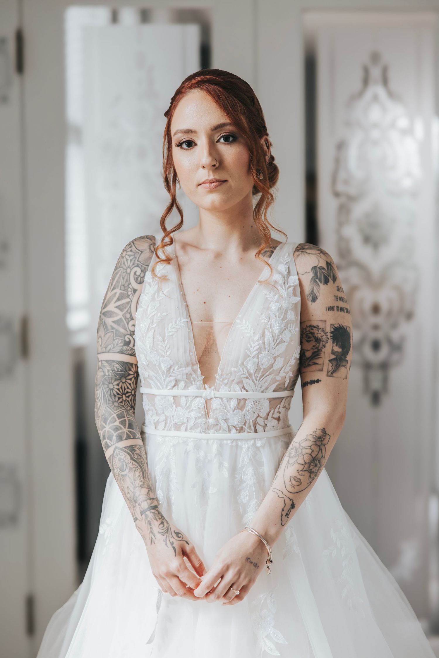 Close up of an intricately detailed white lace wedding dress with floral embellishments.