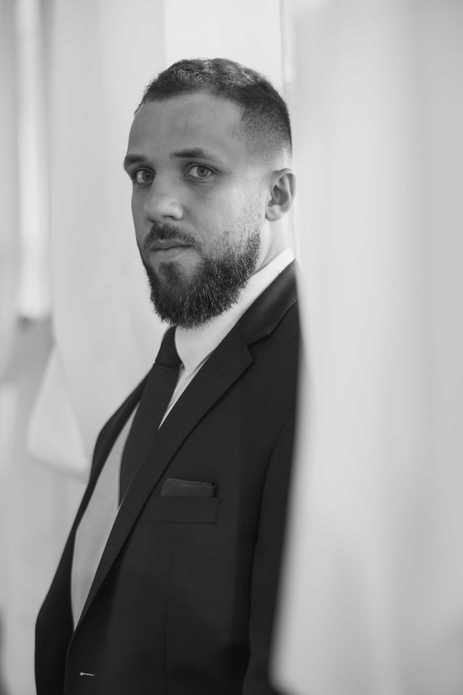 Professional black and white portrait of a bearded man in a formal suit looking to the side.