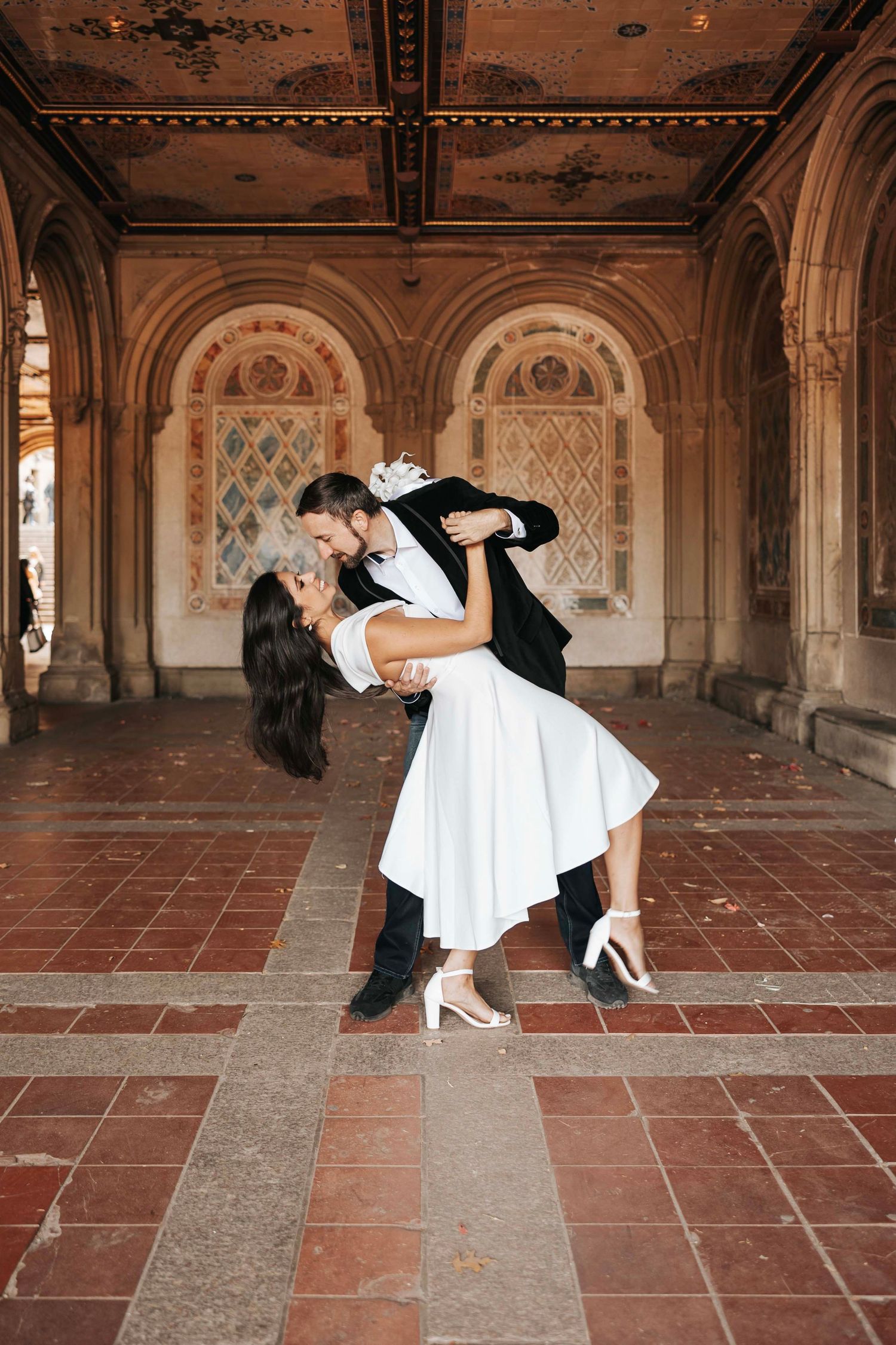 Romantic dance dip pose in front of ornate architectural arches.