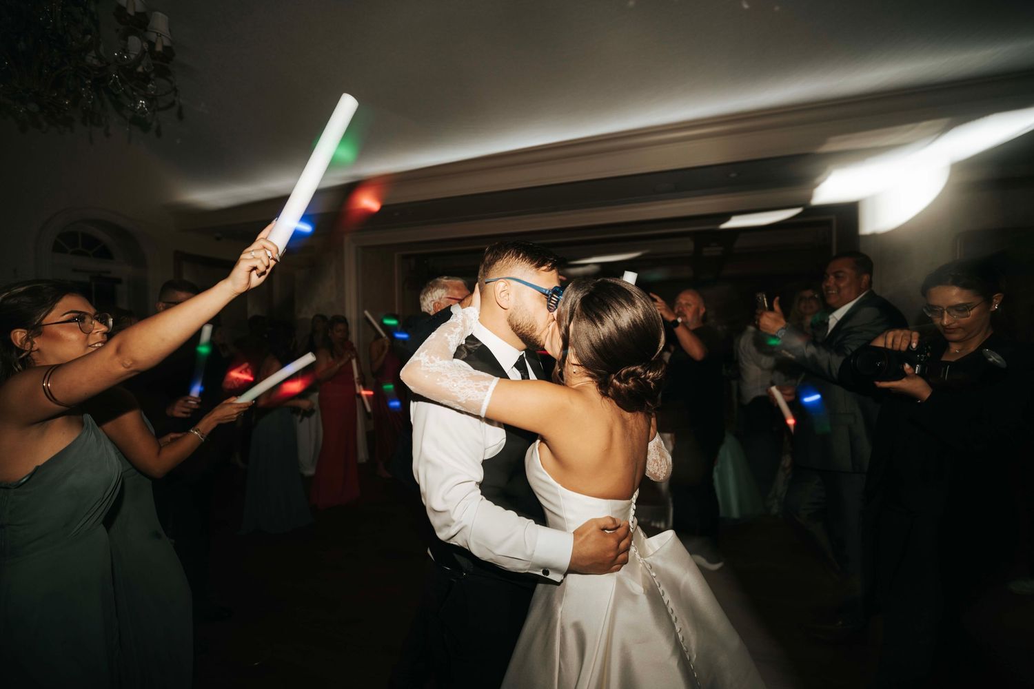 Wedding couple dancing surrounded by guests holding light sabers creating a magical atmosphere.