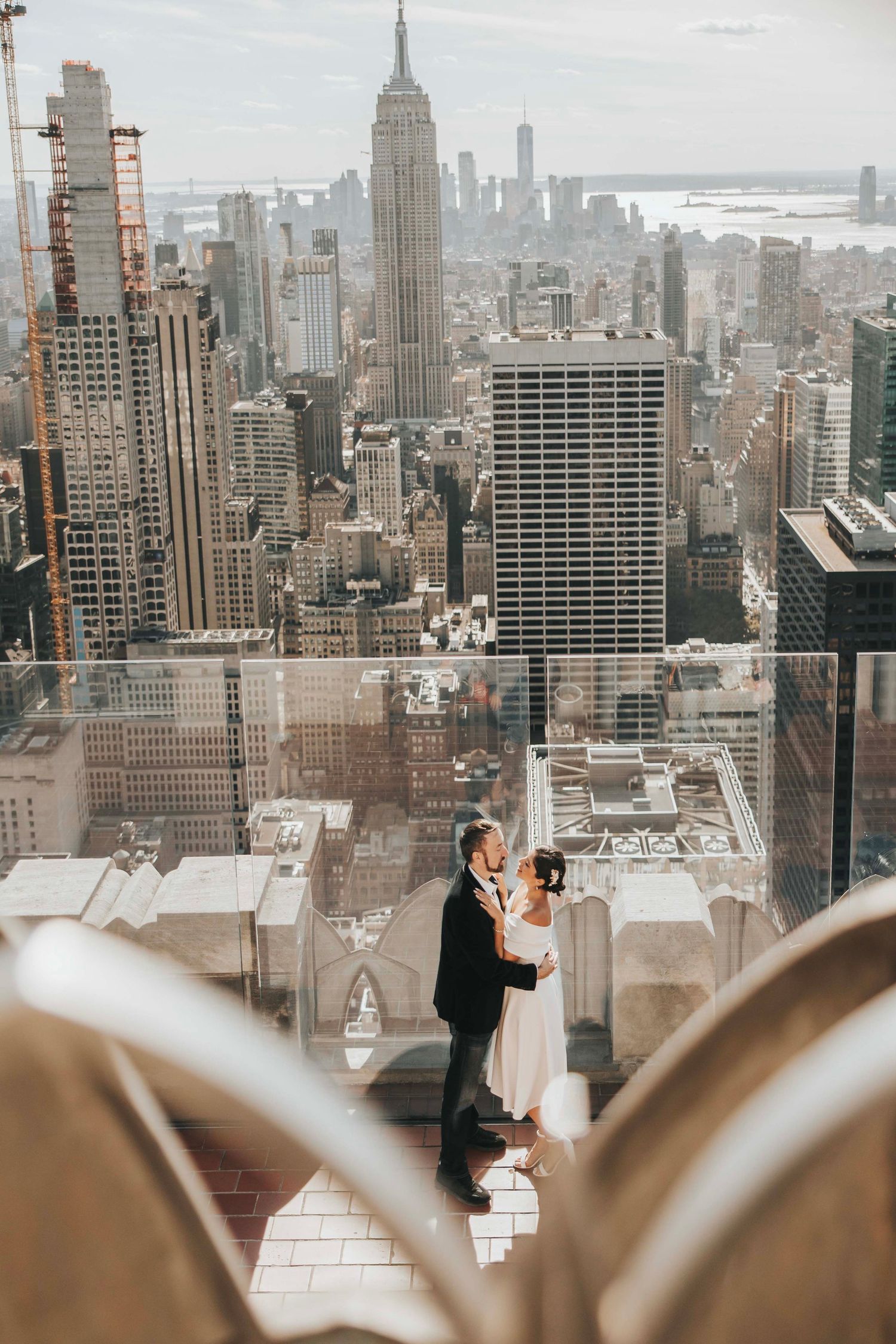 Couple embracing on rooftop with Empire State Building and Manhattan skyline view.