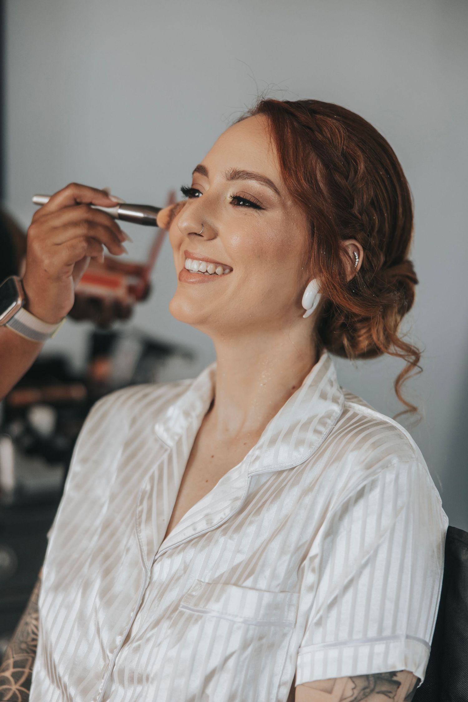 Morning wedding preparations with professional makeup application in white getting-ready robe.