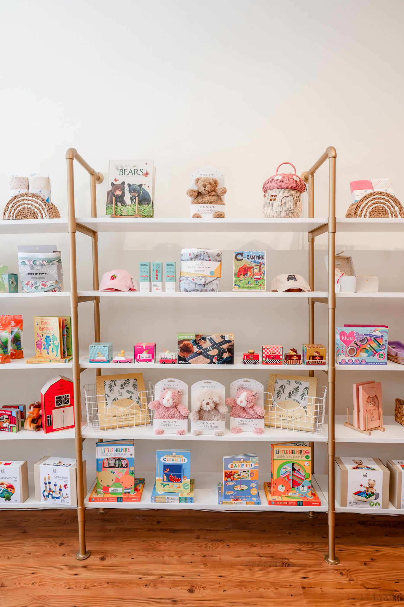 Modern white and gold shelving unit displaying colorful children's toys, books, and decor items on multiple tiers.