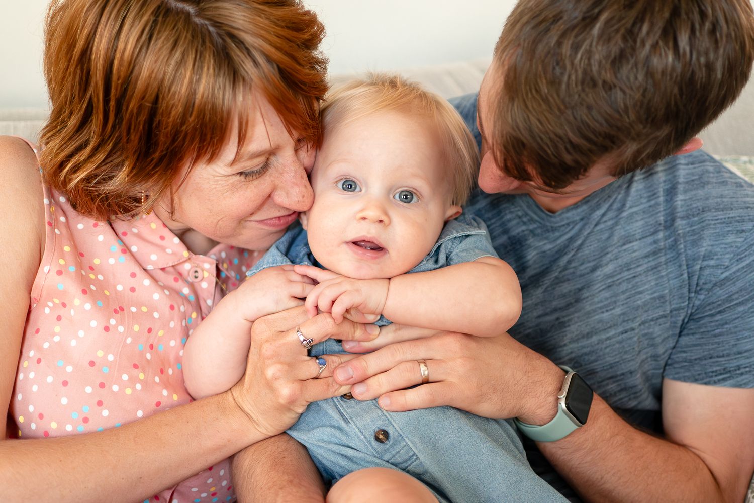 Parents lovingly embracing and kissing their baby in a tender family moment.