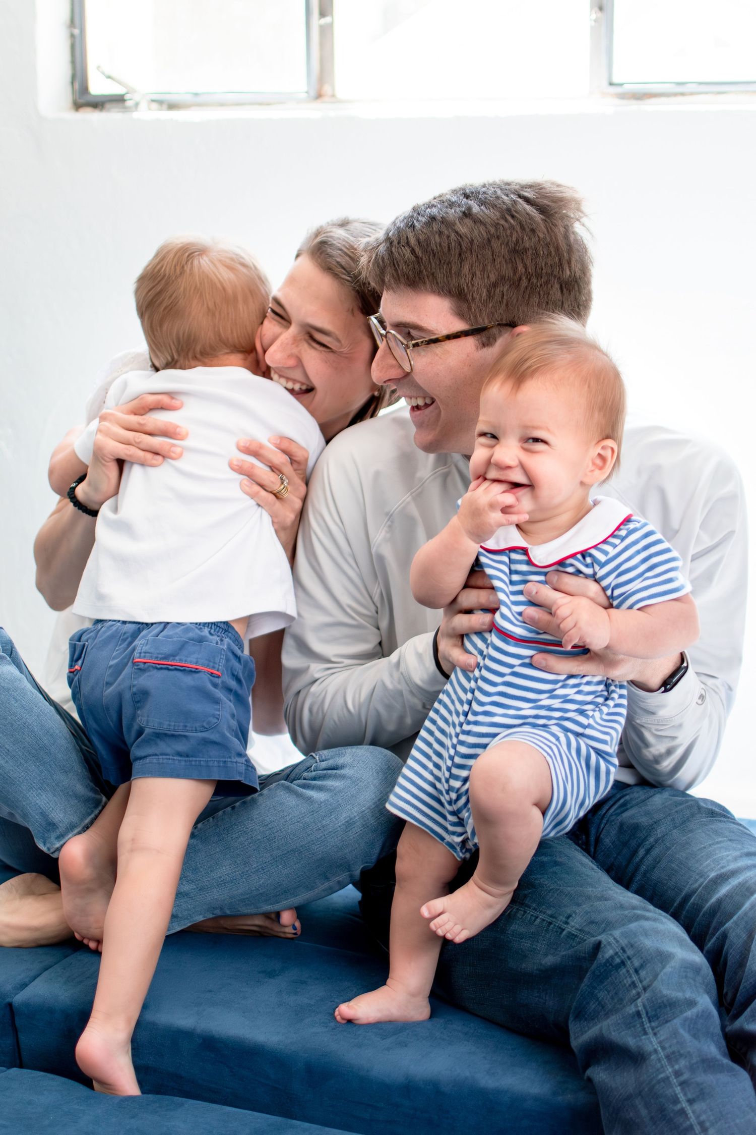 A cheerful family moment shared on a blue couch in a bright room.