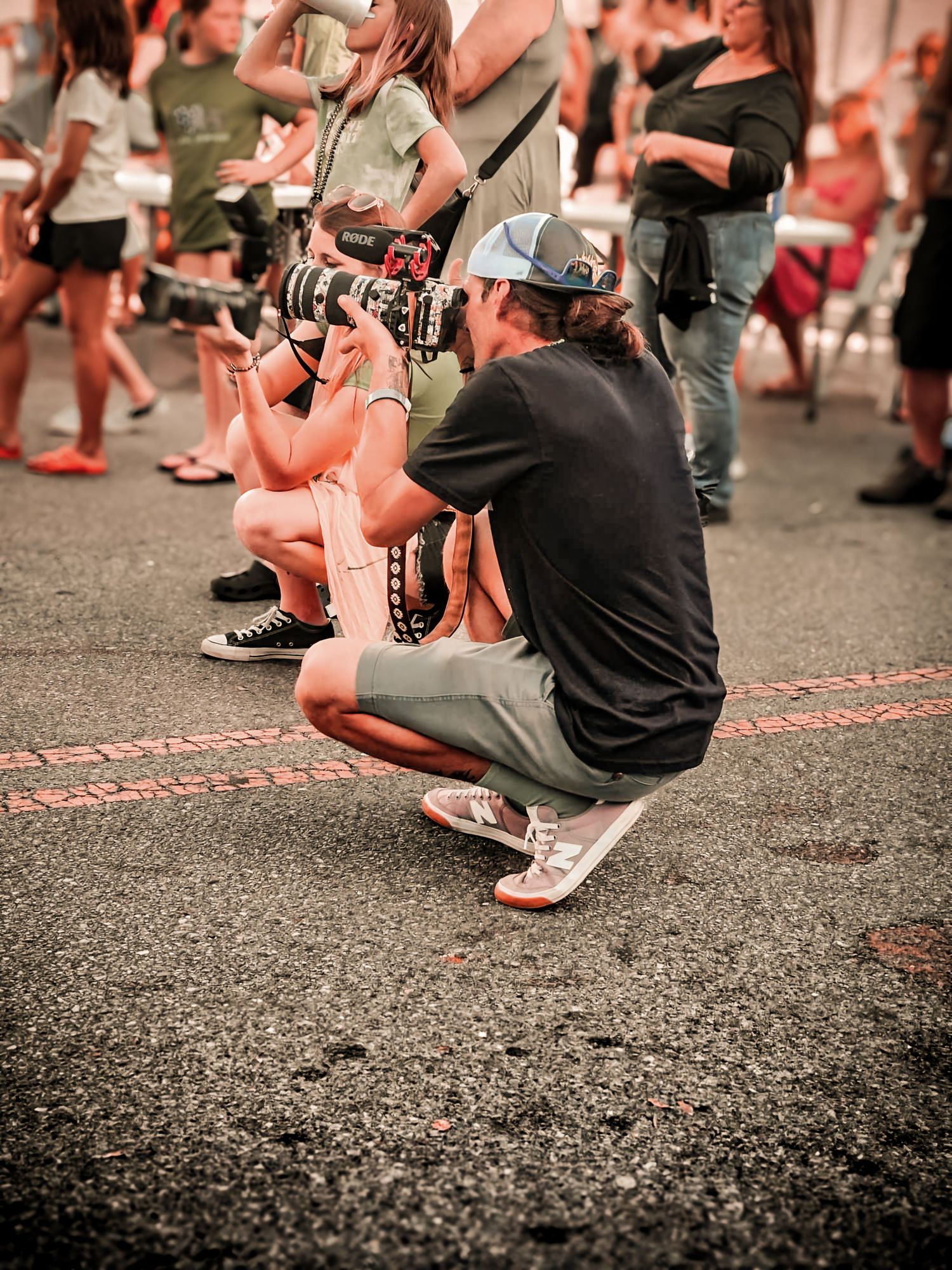 People crouching in a line on pavement photographed from waist level with selective focus and warm tones.