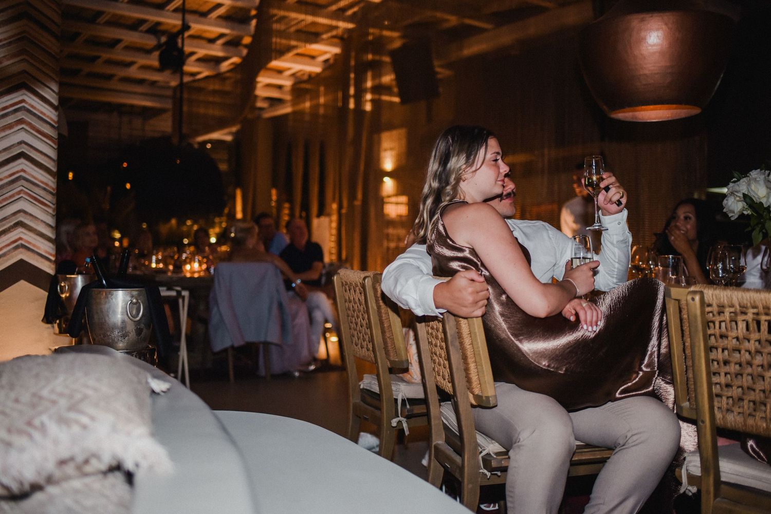 Evening wedding reception in dimly lit rustic venue with wooden beams.