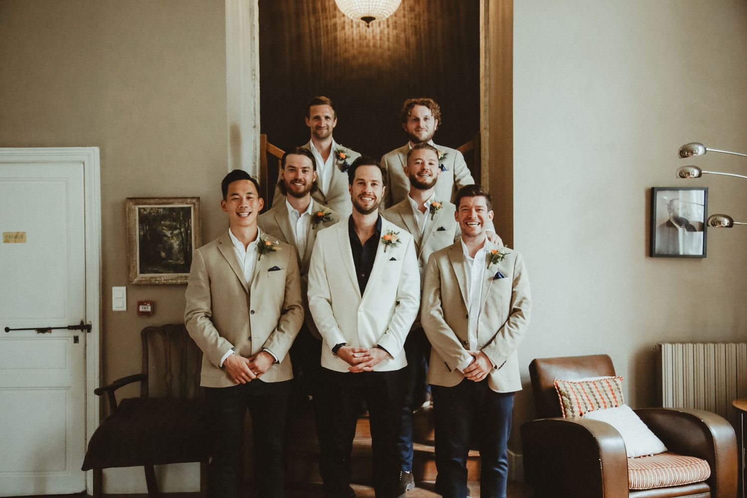 Wedding party smiles for indoor group photo with matching beige and white attire.