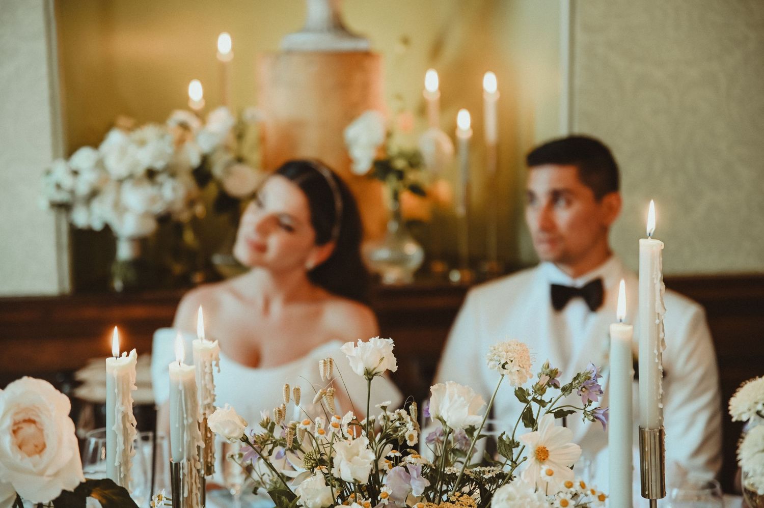 Elegant wedding reception table decorated with tall white candles and floral arrangements at an intimate dinner setting.