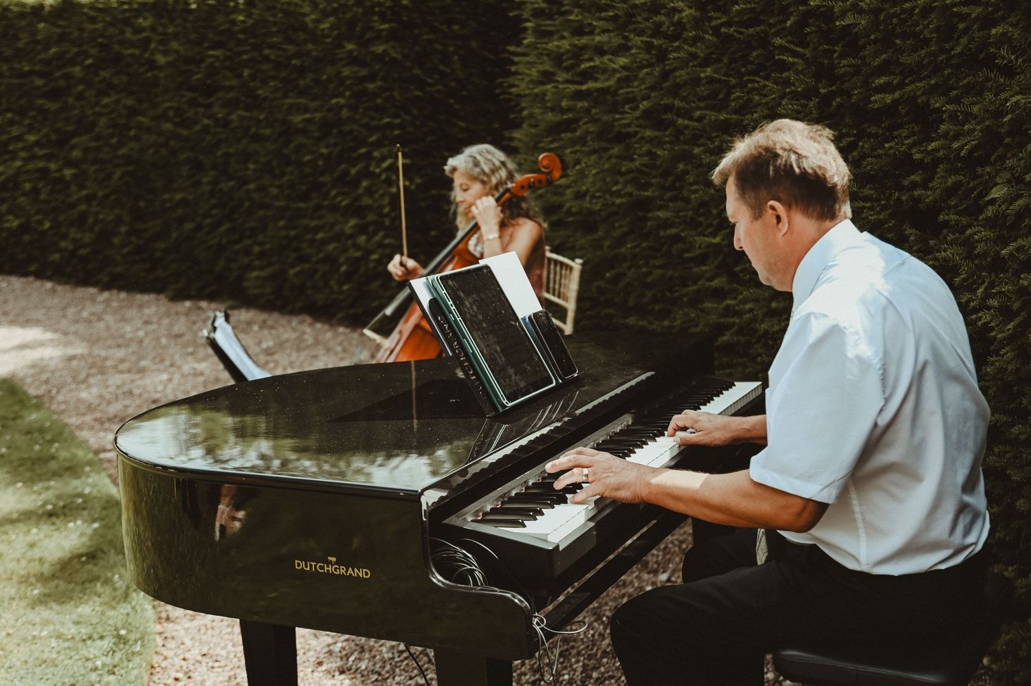 Musician playing piano at an outdoor garden wedding reception.