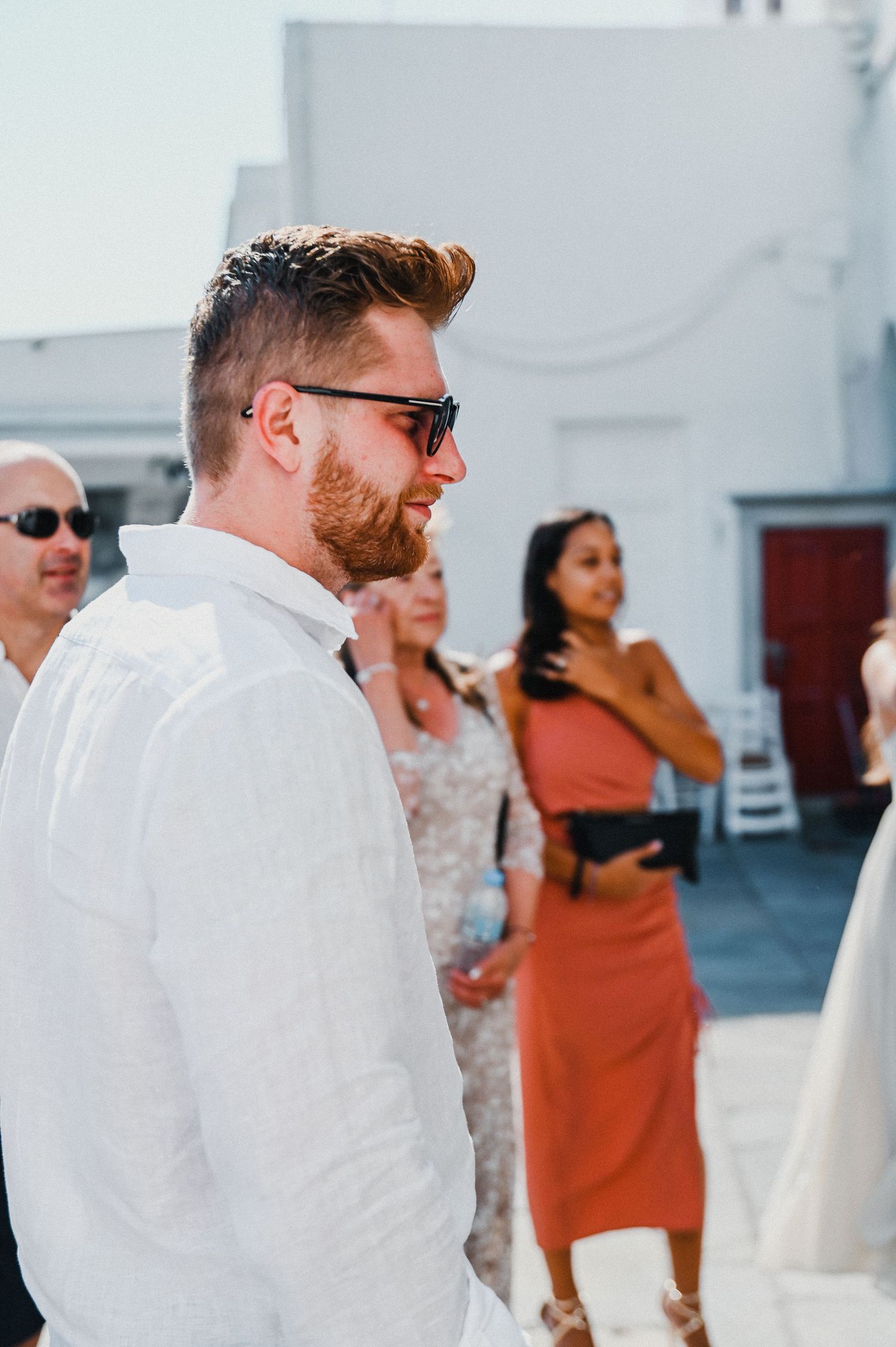 Wedding guests in summer attire gathered on a sunny Mediterranean rooftop.
