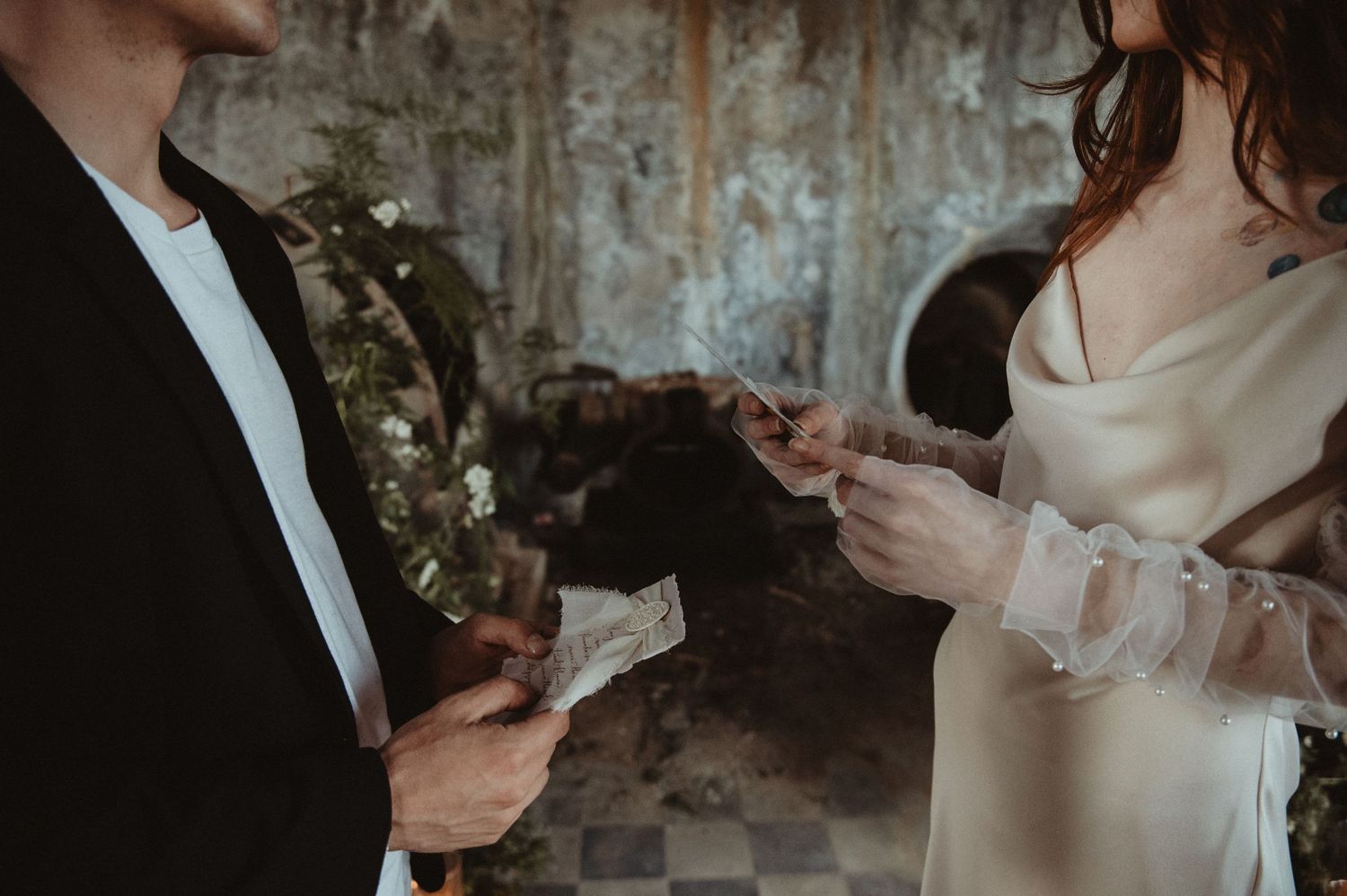 A couple exchanges handwritten vows in an atmospheric space with distressed walls.