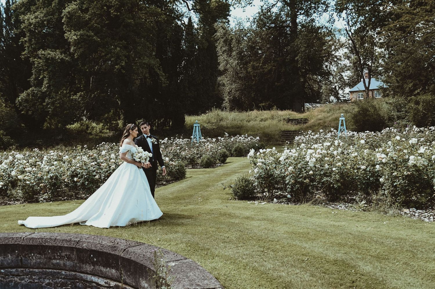 Romantic garden wedding photo with manicured lawns and blooming white flowers.