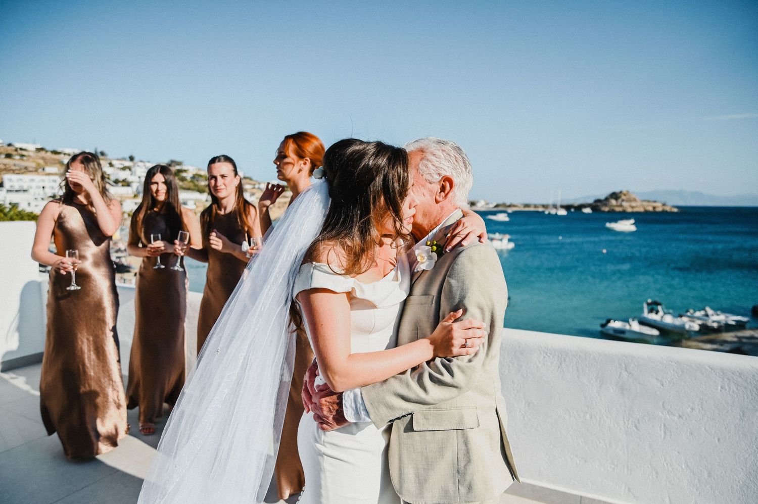 Outdoor beach wedding ceremony with couple kissing as wedding party looks on.