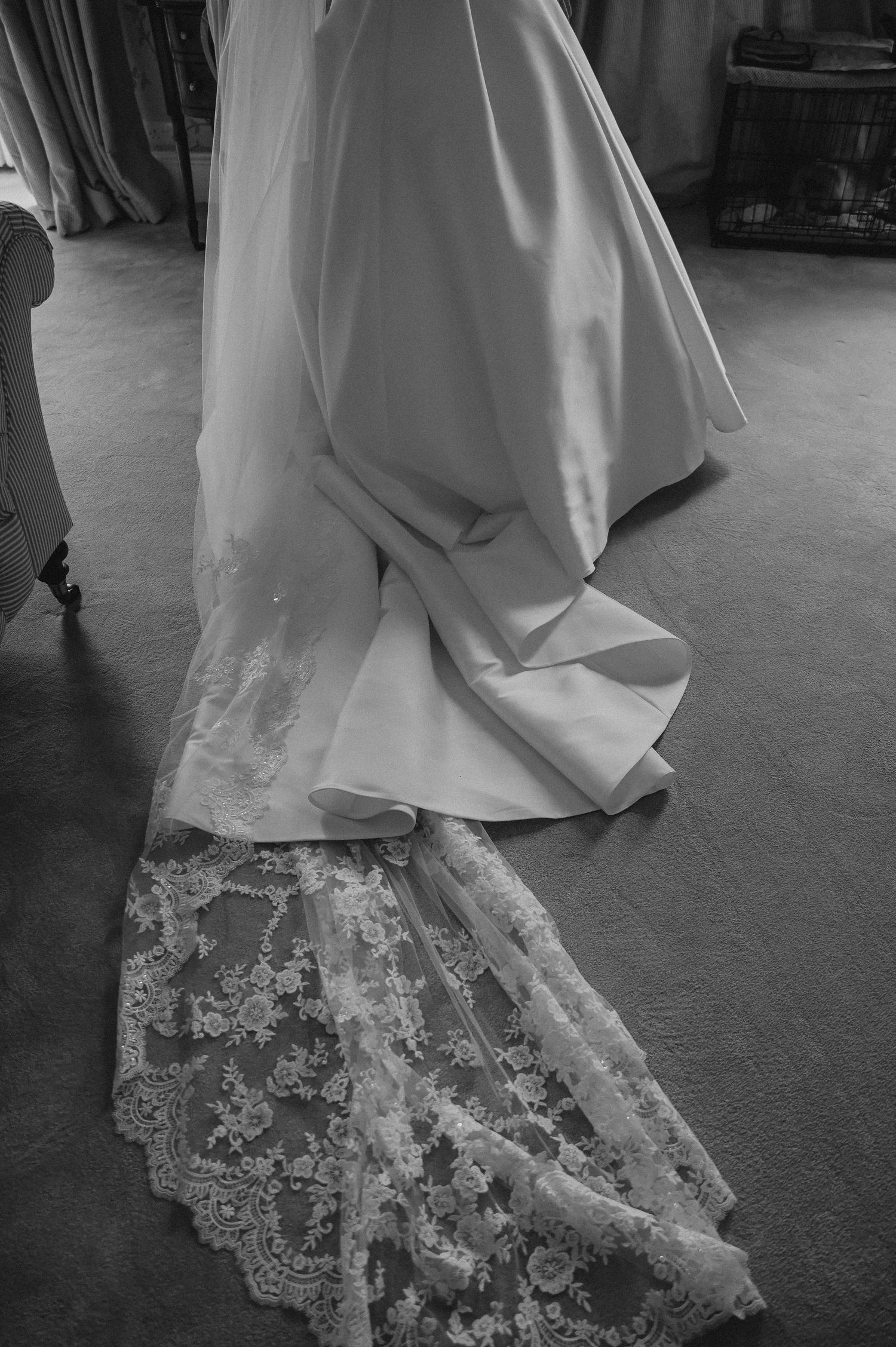 Close-up of a wedding dress train with intricate lace details in black and white.