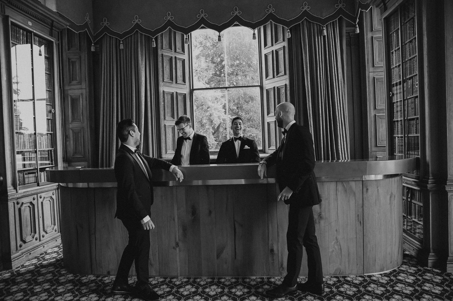 Several people in suits gathered around an elegant vintage bar area.