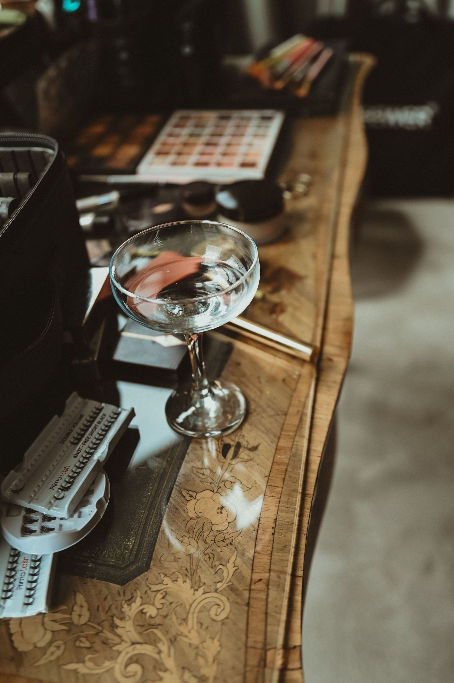 Vintage cocktail glass and bar equipment arranged on an ornate wooden counter.