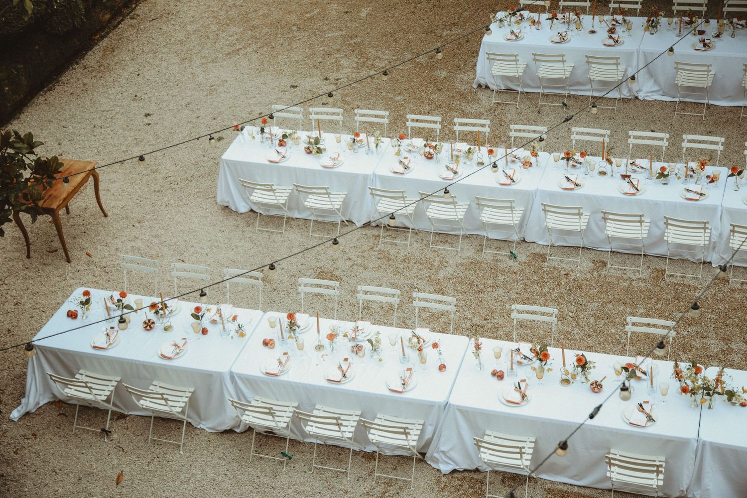 Elegant outdoor wedding reception setup with long white tables and place settings.