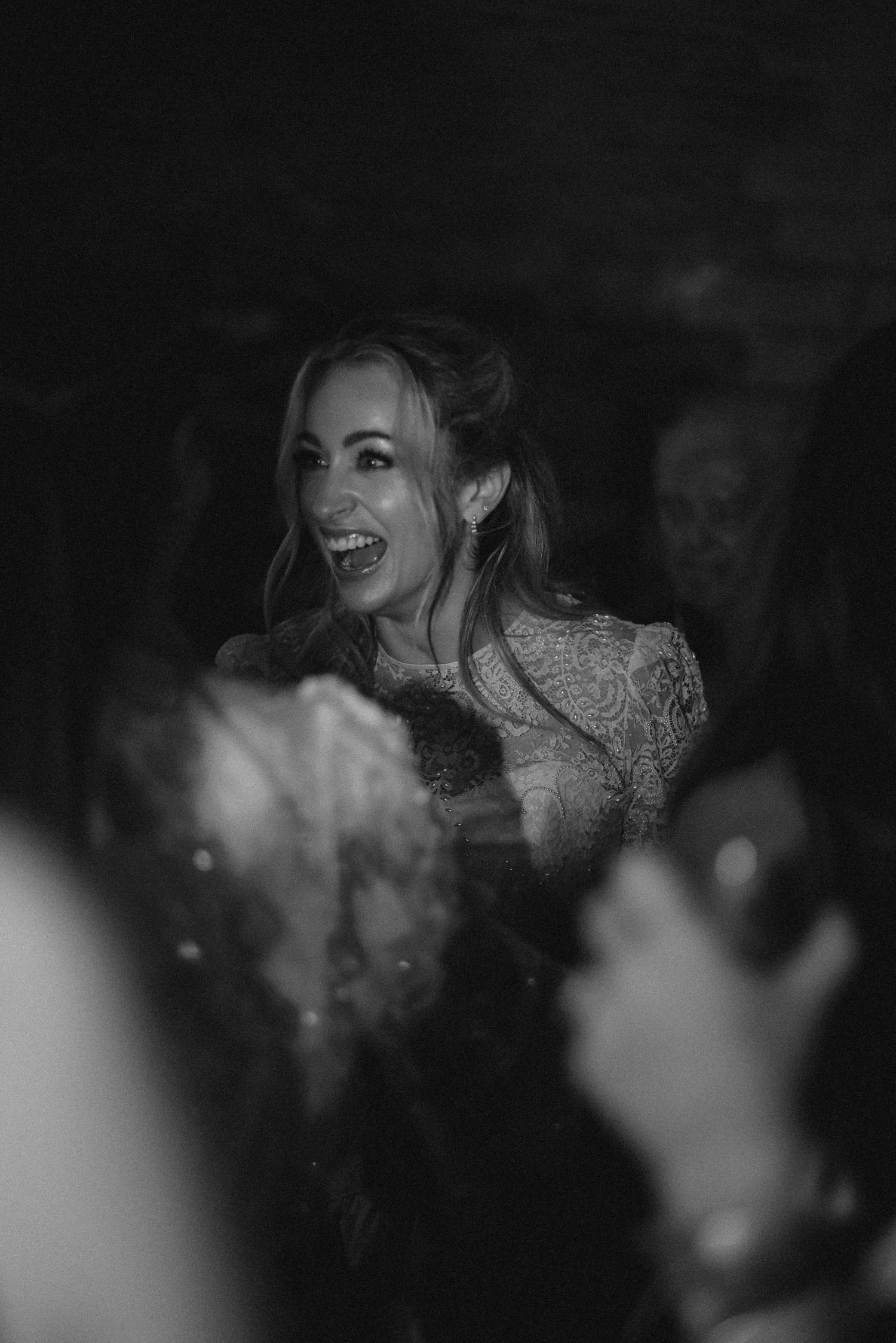 A black and white candid shot of someone laughing during a festive celebration.