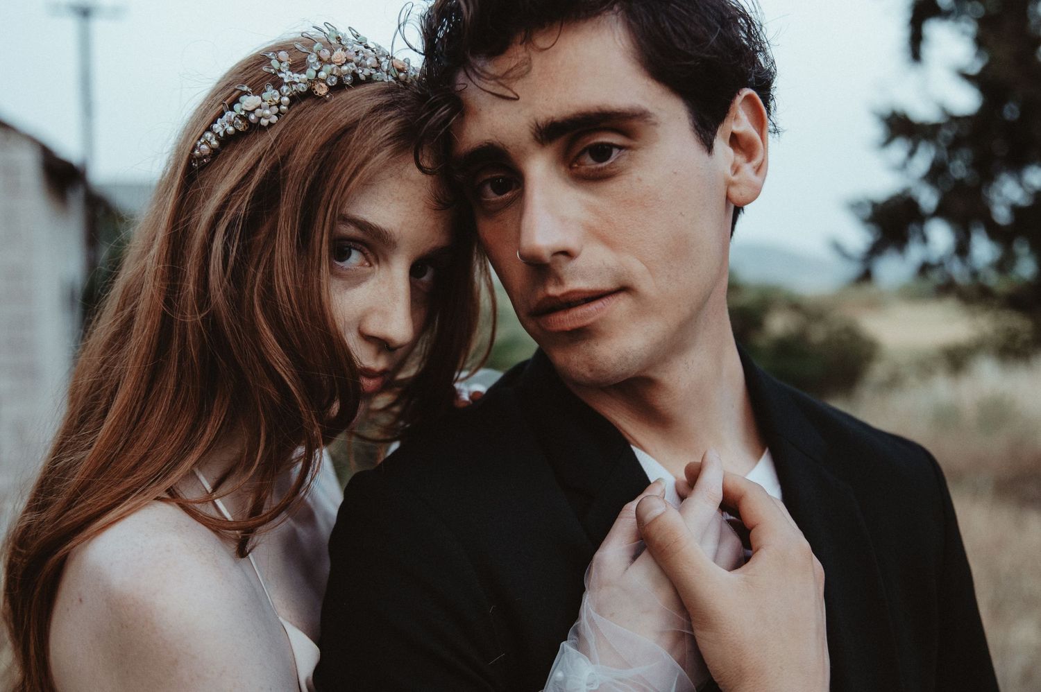 An intimate portrait of a couple in wedding attire sharing a close embrace outdoors.