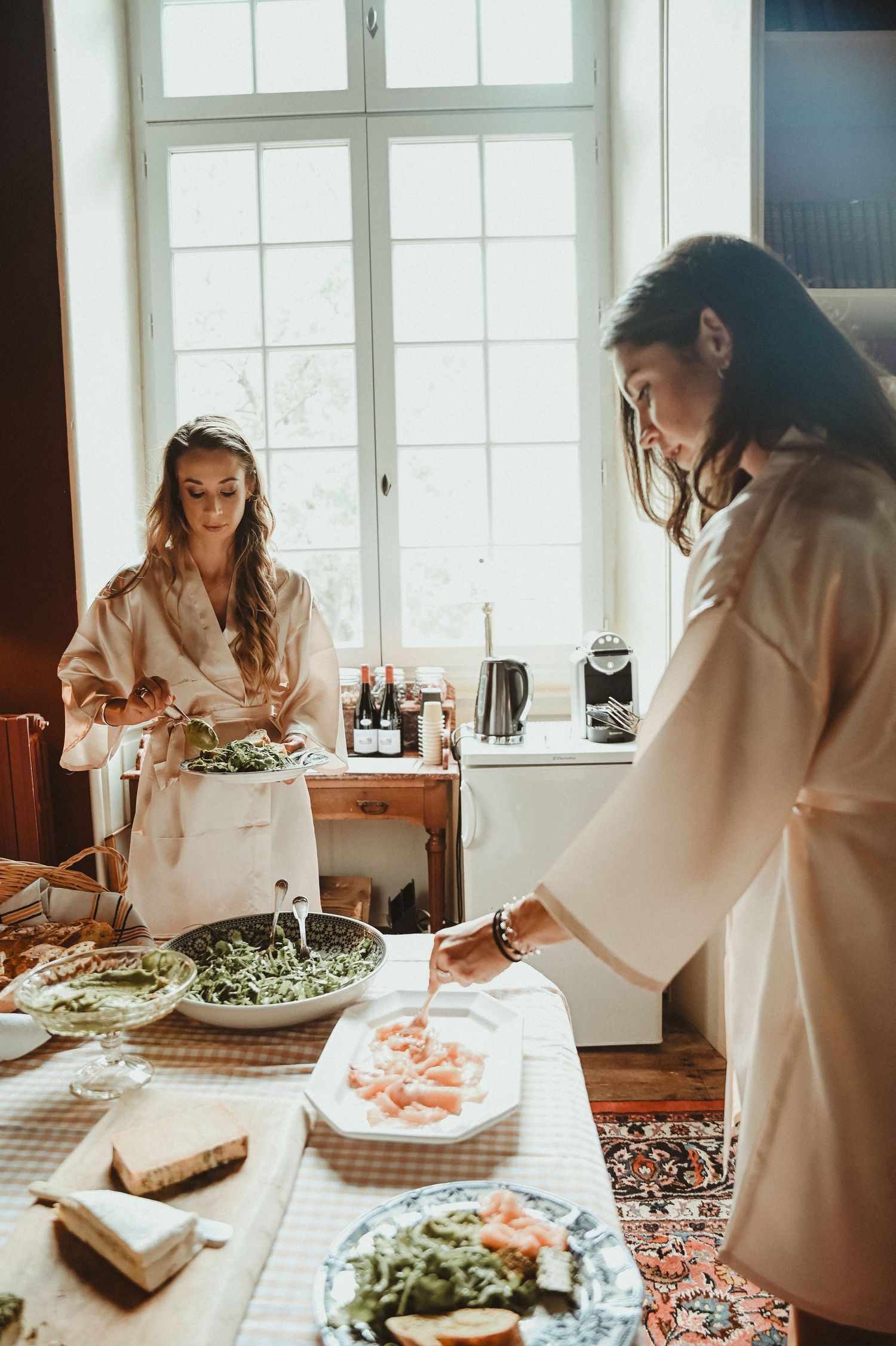 People in robes preparing food at a bright kitchen counter.