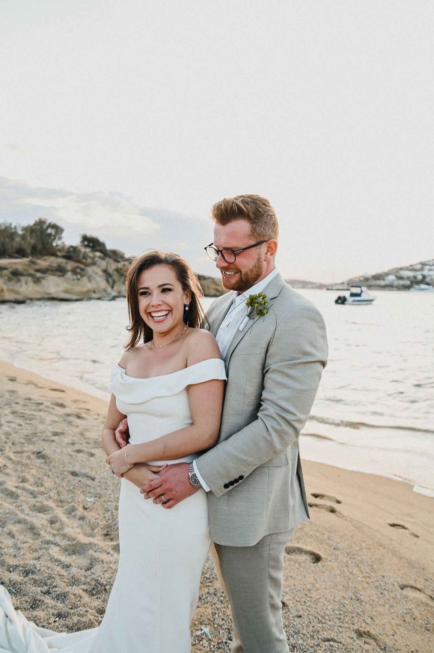 A couple embraces on a scenic Mediterranean beach during their destination wedding.