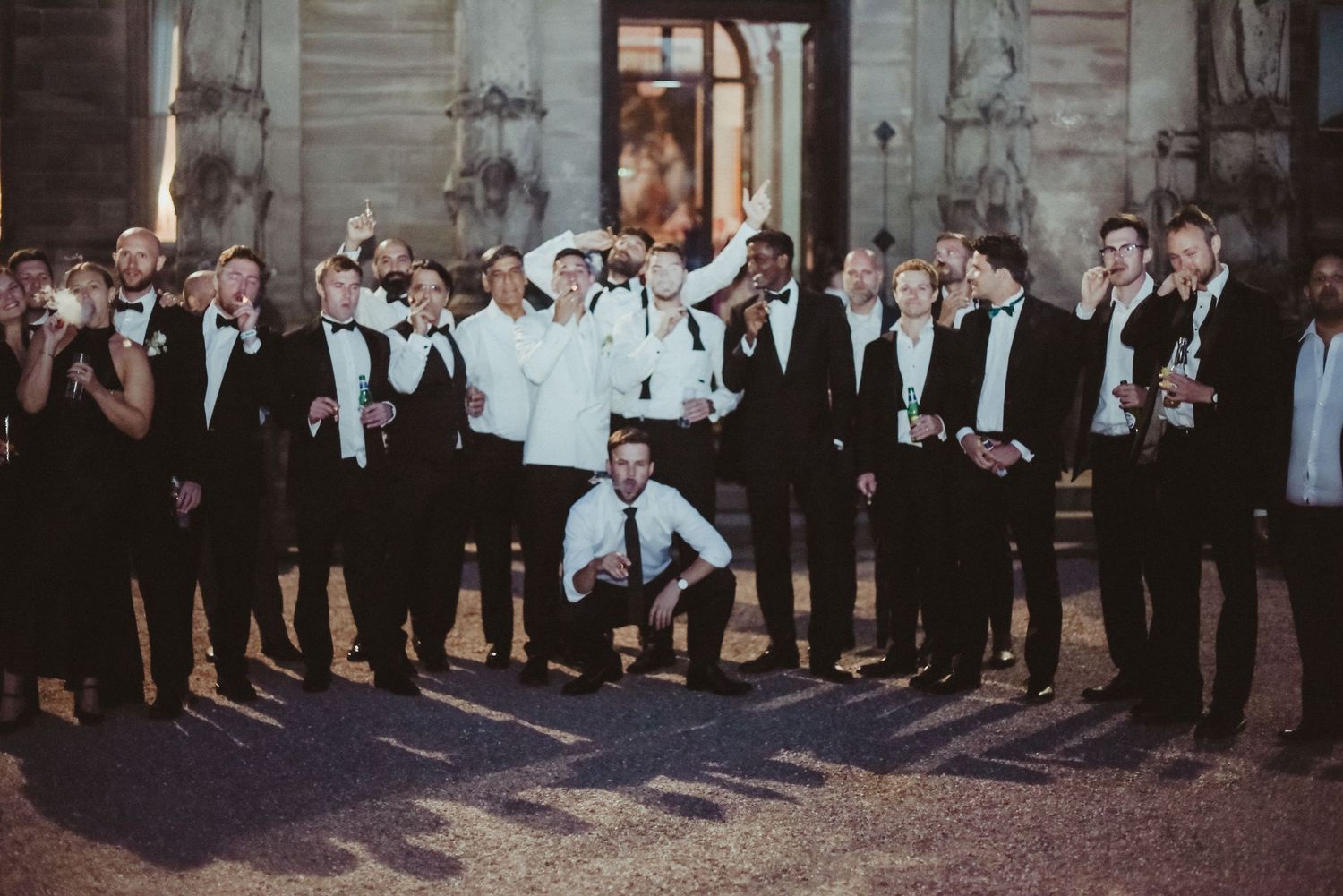 Groomsmen in formal attire pose together at an evening wedding celebration.