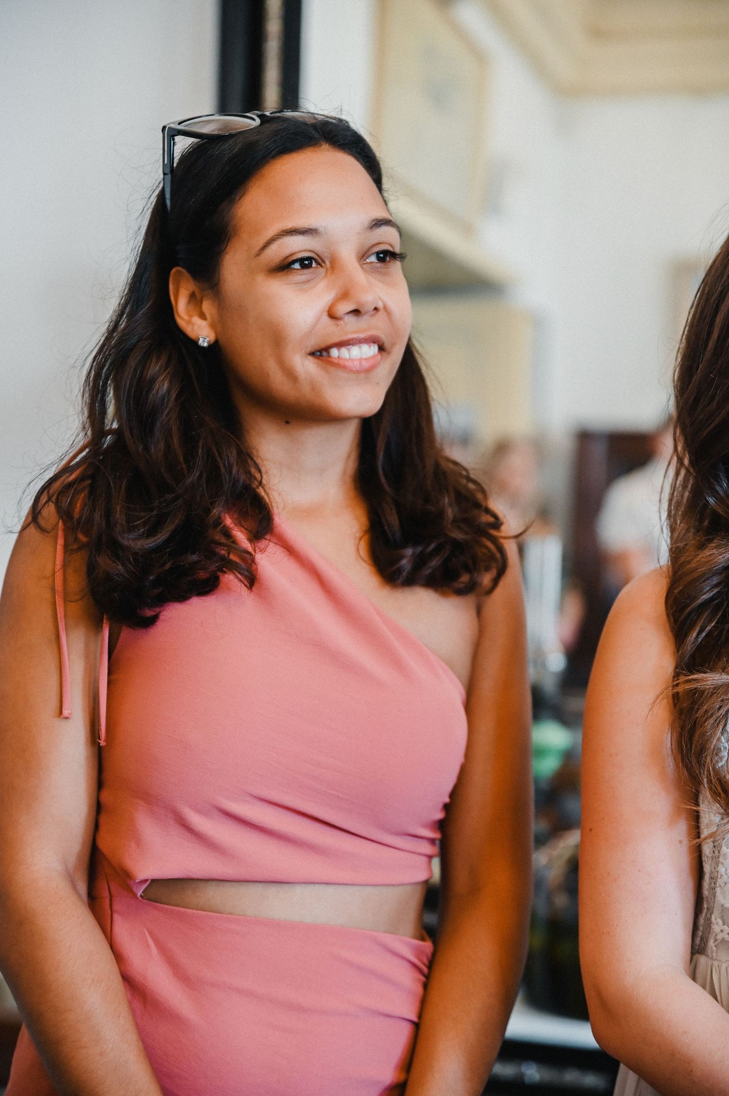 A person wearing a coral pink two-piece outfit smiles warmly.