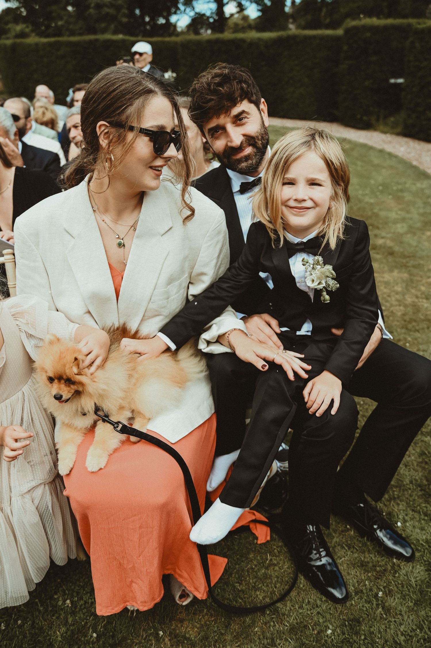 A family relaxing on lawn chairs at an outdoor event with their small Pomeranian dog.