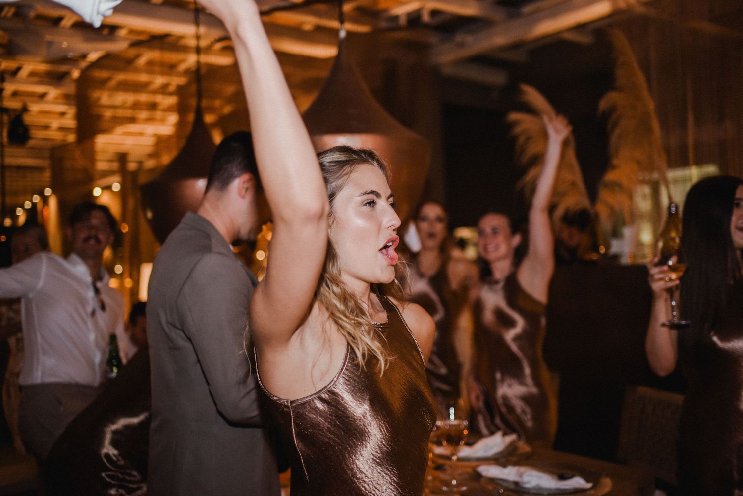 Party guests dancing and celebrating at a wedding reception with atmospheric lighting.