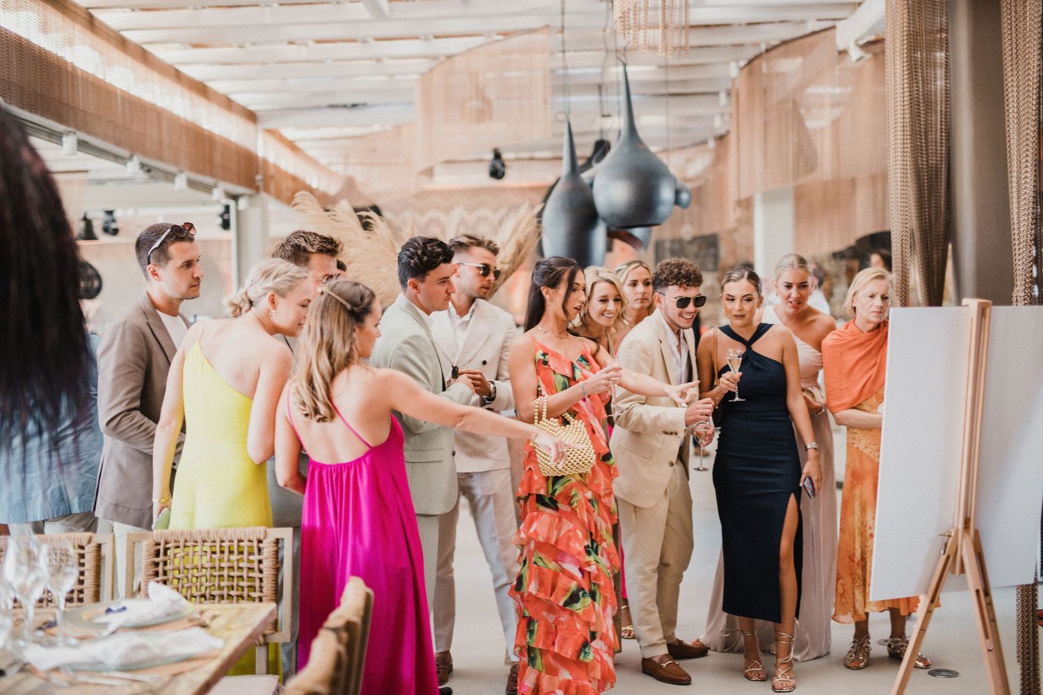 Wedding guests mingling around cocktail tables at an outdoor beach reception.