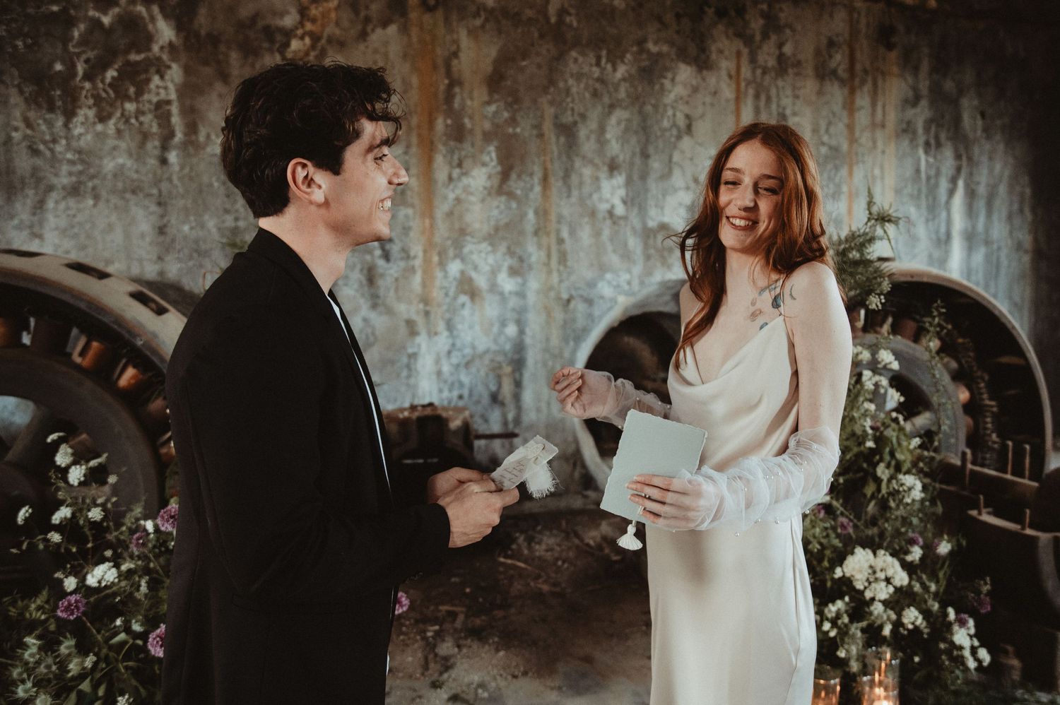 A wedding ceremony in a rustic industrial space with exposed walls and romantic floral decor.