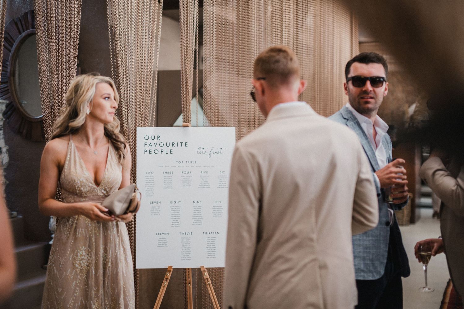 Wedding seating chart displayed on easel at outdoor reception venue.