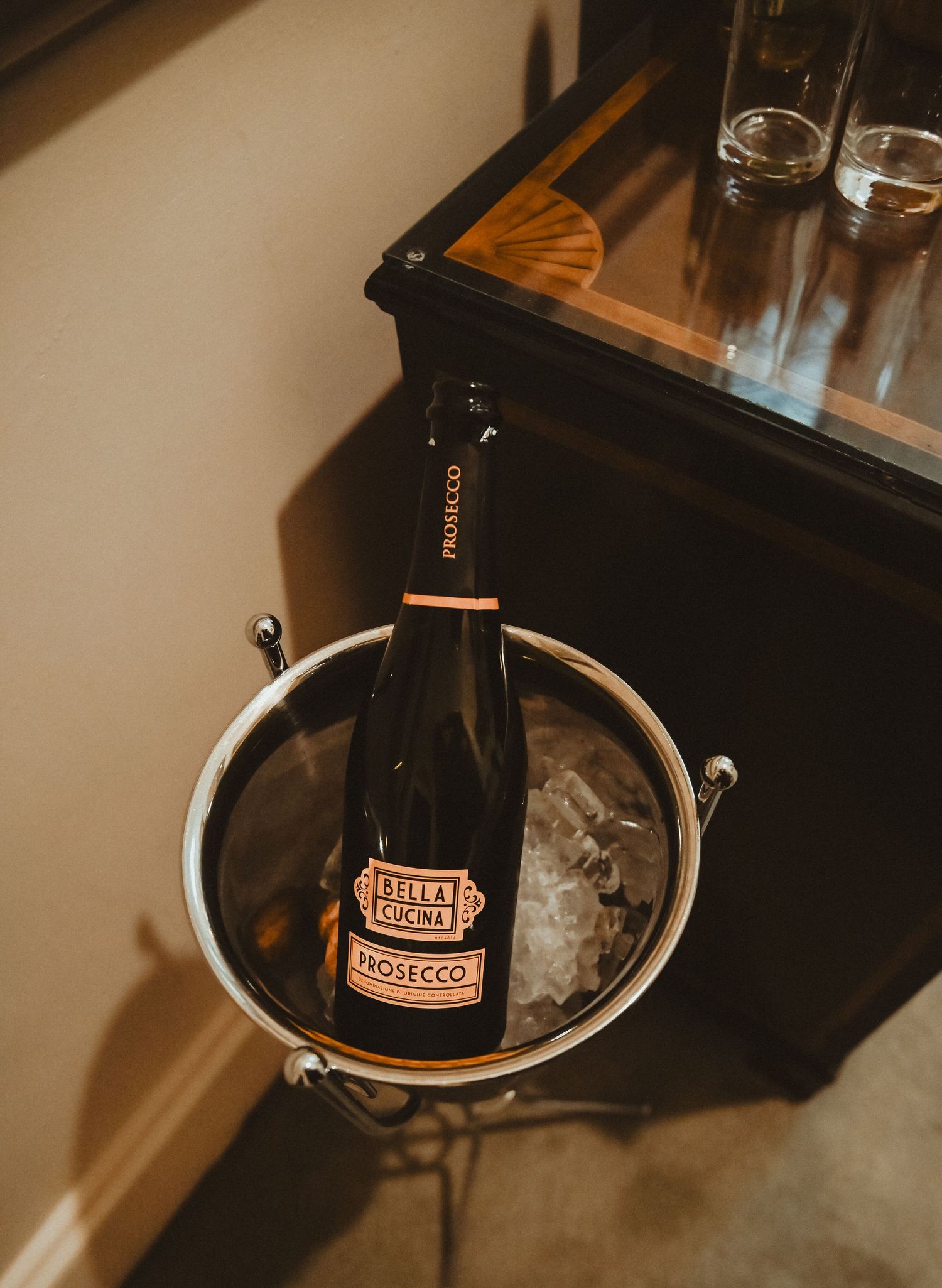 A bottle of champagne chilling in an ice bucket against a dark background.